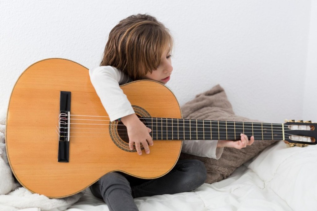 Little girl learning to play classical guitar