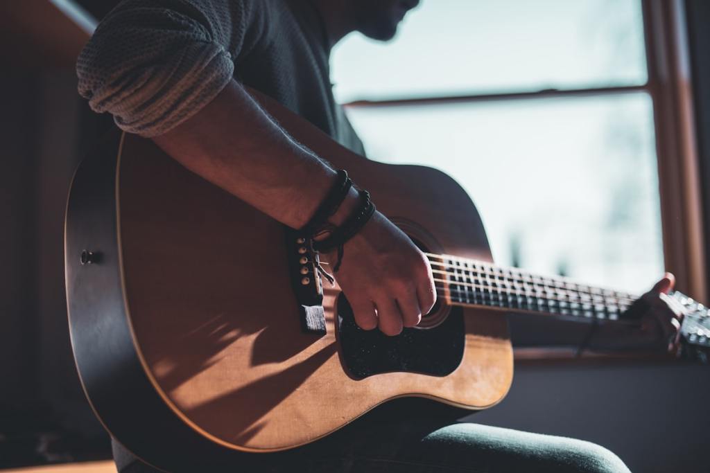 Close-up of a hand strumming an acoustic guitar, illustrating rhythm and strumming technique